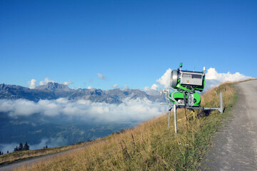 On a bright day, there is a cannon for making artificial snow on the mountainside