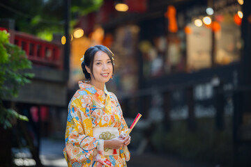 Asian woman try to wear Japanese kimono with the traditional Japanese village background