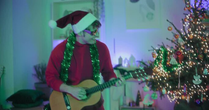 Man dancing while playing guitar at illuminated home during Christmas