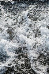 Detail of the splashes of water falling from the jet of a fountain on the surface. Frozen water movement. High speed. Vertical.