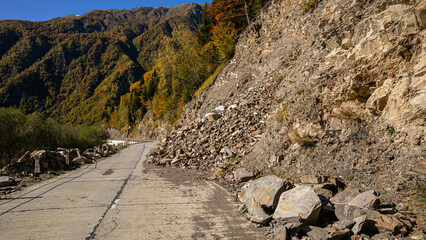 A road partially obstructed by a rockslide illustrates the concept of natural hazards and their...