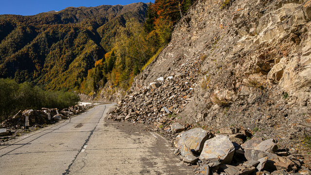 A road partially obstructed by a rockslide illustrates the concept of natural hazards and their impact on infrastructure