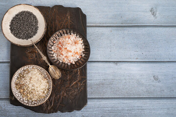 different types of salt. Three different types of salt in handmade craft plates on a clay board. White herbal sea salt, pink Himalayan and black Maldon Thursday. Top view, flat lay, copy space