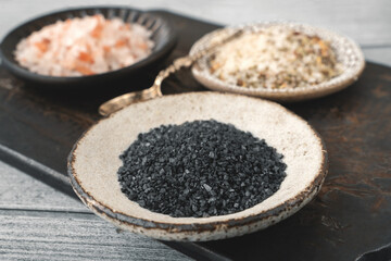 different types of salt. Three different types of salt in handmade craft plates on a clay board. White herbal sea salt, pink Himalayan and black Maldon Thursday.