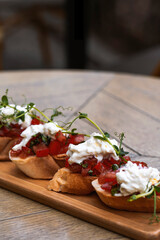 canape with tomato and feta cheese on a wooden table in a restaurant юBruschetta with tomatoes .mozzarella and arugula