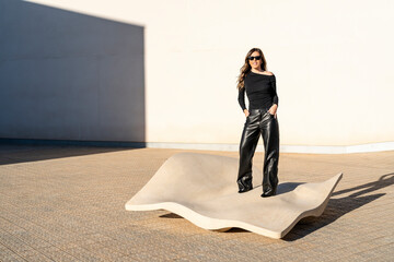 Full length portrait of pretty and elegant woman dressed in black in the sun outdoors in a...