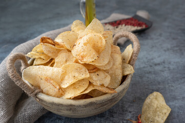 Potato spicy chips in a handmade clay bowl with peppers. 