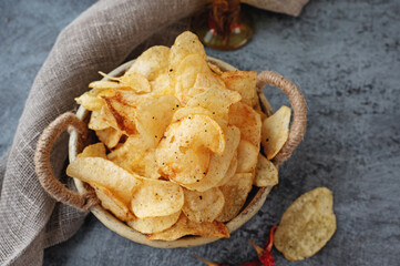 Potato spicy chips in a handmade clay bowl with peppers. 
