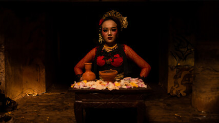 a female dancer sits gracefully and begins her ritual in front of beautiful offerings