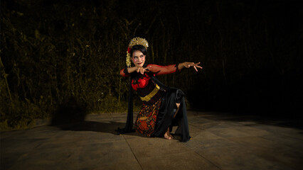 a Balinese dancer wearing a red dress with artistic details that add uniqueness to her appearance