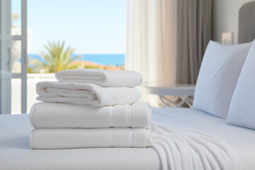 Fototapeta premium clean white towels on a hotel bed in a bright cozy room overlooking the sea