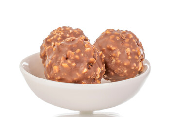Three chocolates  on a ceramic white saucer, macro, isolated on a white background.