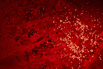 Abstract Christmas background made of red velvet fabric with red sparkles. - obrazy, fototapety, plakaty