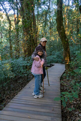 Back view of joyful mother and daughter walking on nature trail,