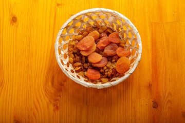 Dried apricots and raisins in a wicker plate on a wooden table after the end of Ramadan
