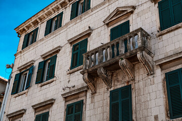Fototapeta na wymiar typical mediterranean european building, stone walls with green wooden sutters, streets of old town kotor in montenegro, tiny balcony
