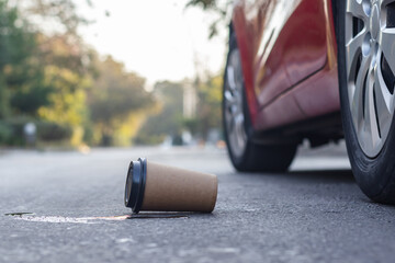 Waste coffee cup thrown on the road by a car driver.Environmental pollution concept