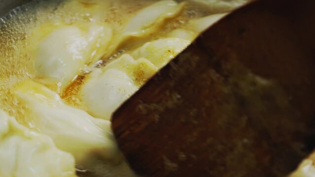 Vareniki dumplings are cooked in a saucepan in boiling water with cumin and turmeric. Close-up.
