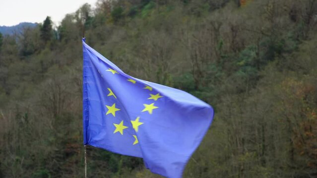 The European Union flag flutters in the wind on a mountain peak in Georgia. Conquering a mountain peak with the EU flag