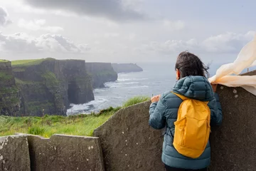 Foto op Canvas Woman on her back with backpack enjoying a splendid view from the top of the Mother's cliff in Ireland © Alberto Marrupe