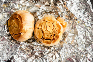 Roasted Heads of Garlic on Crumpled Aluminum Foil: Roasted garlic bulbs drizzled with extra virgin olive oil and sea salt on tin foil