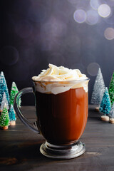 Spiced Christmas Coffee Topped with Whipped Cream: Large glass mug of freshly brewed spiced coffee surrounded with miniature Christmas trees