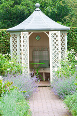 Summer time and the living is easy- white trellis wooden summerhouse in domestic garden set up with...