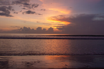 Naklejka premium A tranquil beachscape at sunset with soft pastel colors in the sky reflecting on gentle ocean waves.