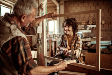 Obraz na płótnie Canvas Little grandson having fun with grandfather in a carpentry shop