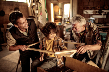 Three generations of men in a woodworking workshop