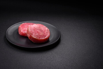 Round shape steaks of raw juicy tuna with salt and spices