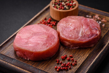 Round shape steaks of raw juicy tuna with salt and spices