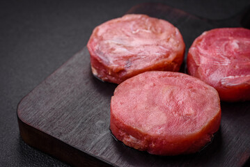 Round shape steaks of raw juicy tuna with salt and spices