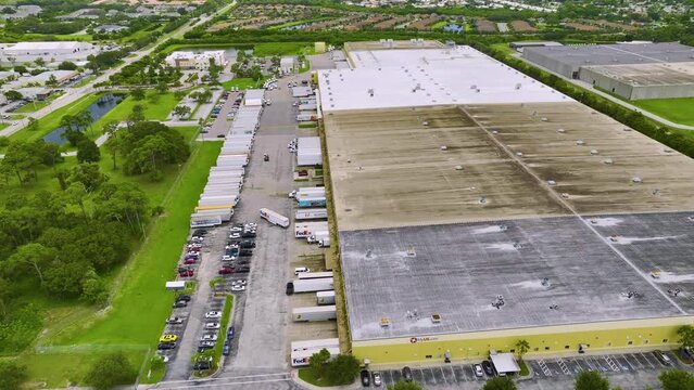 Top view of giant logistics center with many commercial trailer trucks unloading and uploading retail products for further shipment. Global economy concept