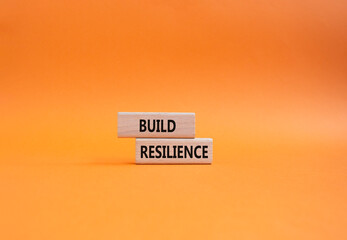 Build resilience symbol. Wooden blocks with words Build resilience. Beautiful orange background....