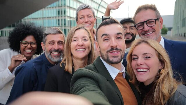 Big group of business people smiling and waving hands on a video call. Crowd of business people greeting and looking at camera. Startup corporate team having fun. Well dressed executive firm partners