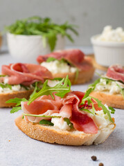 Sandwiches on baguette with jamon, cream cheese and arugula. Traditional spanish breakfast.