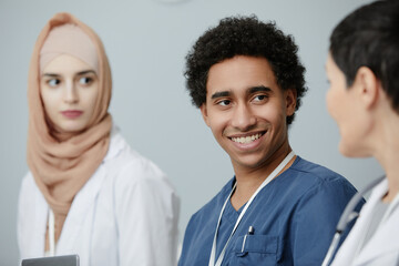 Portrait of young Middle Eastern man sitting in audience at medical seminar and smiling, copy space