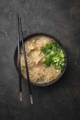 Appetizing Thai soup with gyoza, noodles and herbs.