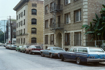Grainy 1980s film photo of brick apartment buildings on Ingraham Street near downtown Los Angeles,...