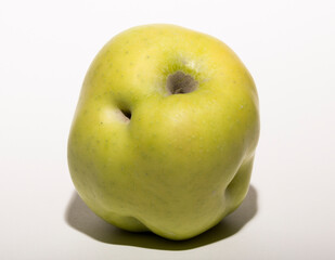 Ugly mutant apple. The fruit is yellow on a white background.
