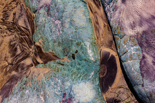 Contrasting brown and turquoise rocks on the beach in an interesting abstract pattern.