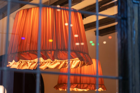 zwei orangefarbene Lampenschirme hinter einem Fenster 