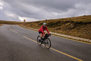 Female cyclist in bike packing tour.Bikepacking travel.Female cyclist is riding through foggy mountain landscape.Adventure cycling concept. Woman cycling in the nature.Transalpina road.Par&acirc;ng Mountain