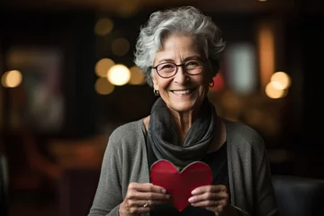 Fotobehang Senior lovely woman holds in hands a paper heart, during celebrating St. Valentines Day © Oleksandr Kozak