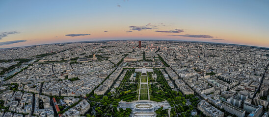 Paris, France, July 1, 2022. Breathtaking view of the city from above, at the foot of the Eiffel Tower, in the Champs de Mars gardens. Blue hour. Large format panoramic photo.