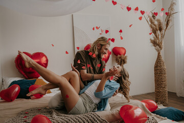 Playful loving couple bonding and throwing heart shape confetti while celebrating Valentines day 