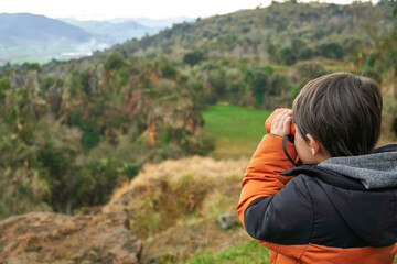 Elementary child exploring the mountains with binoculars. 