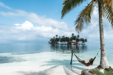 Woman lying on an hammock in an idyllic tropical beach - obrazy, fototapety, plakaty