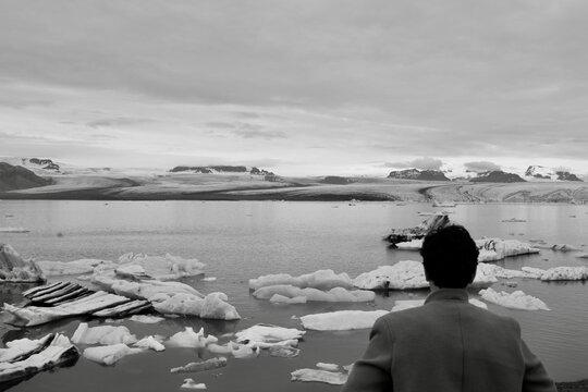 Black and white picture with man infront of glacier lake